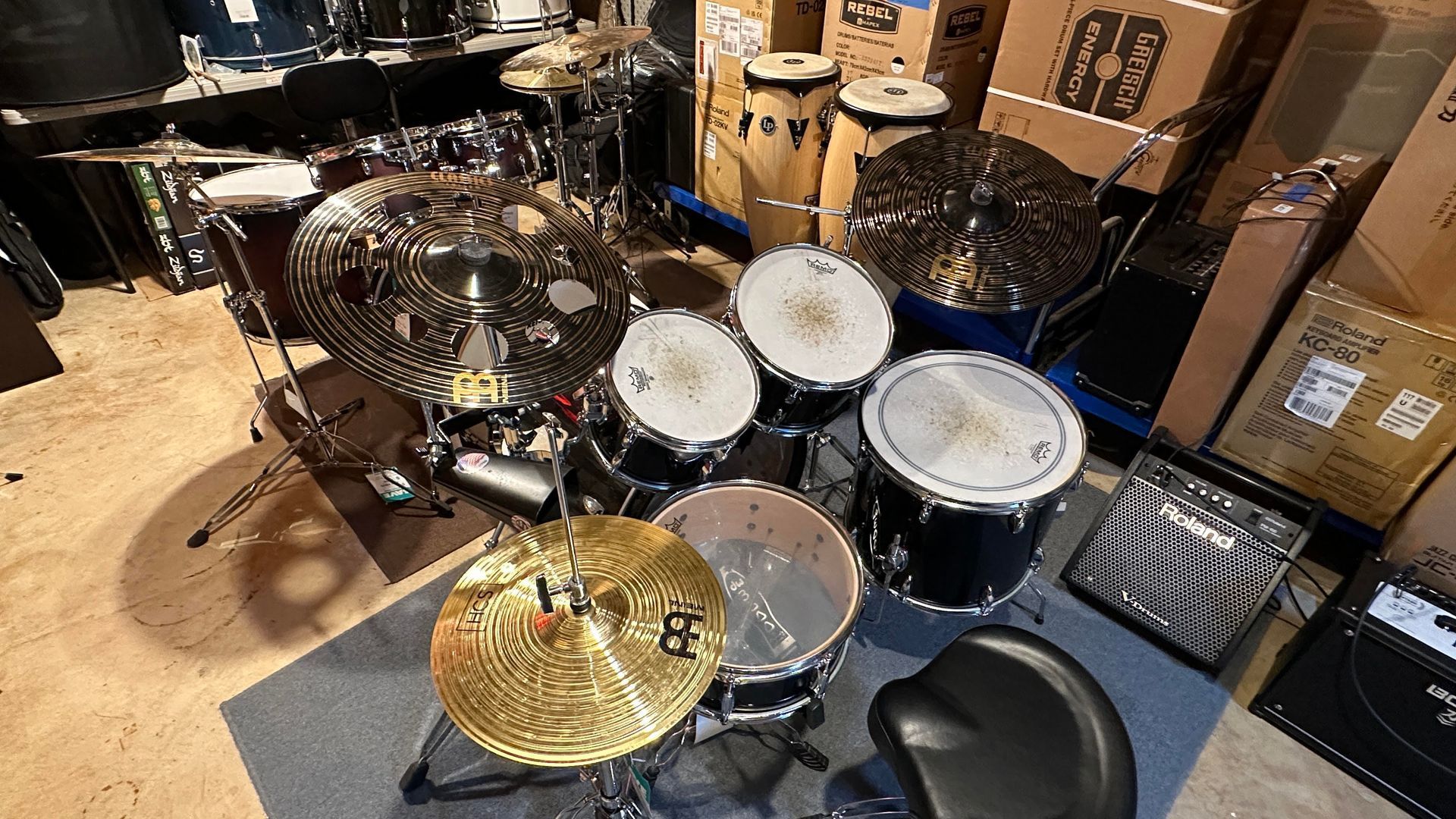 Drum set with multiple cymbals, toms, and snare drum on a rug. A black drum throne sits nearby.