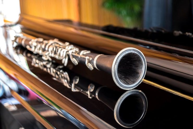 Clarinet resting on a black, shiny piano.