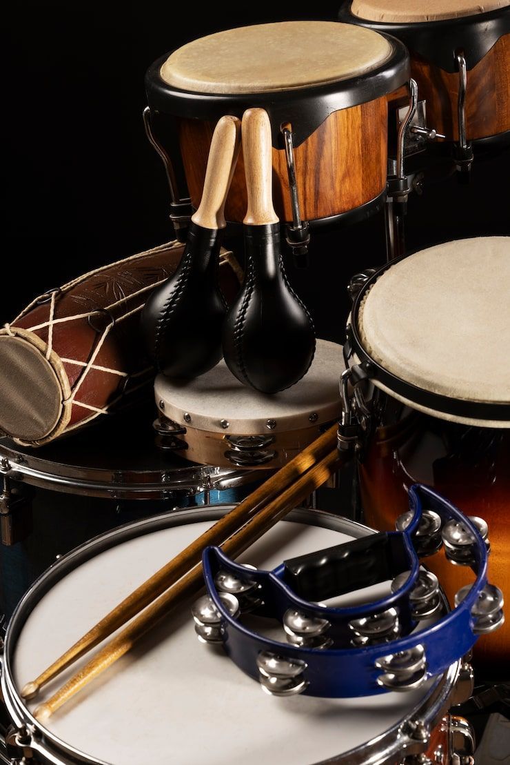 Percussion instruments including drums, maracas, and a tambourine arranged on a dark background.