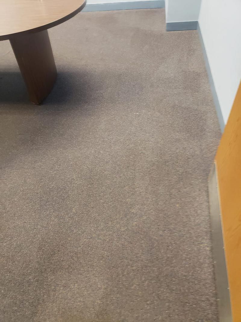 A brown carpeted floor with a wooden table in the background.