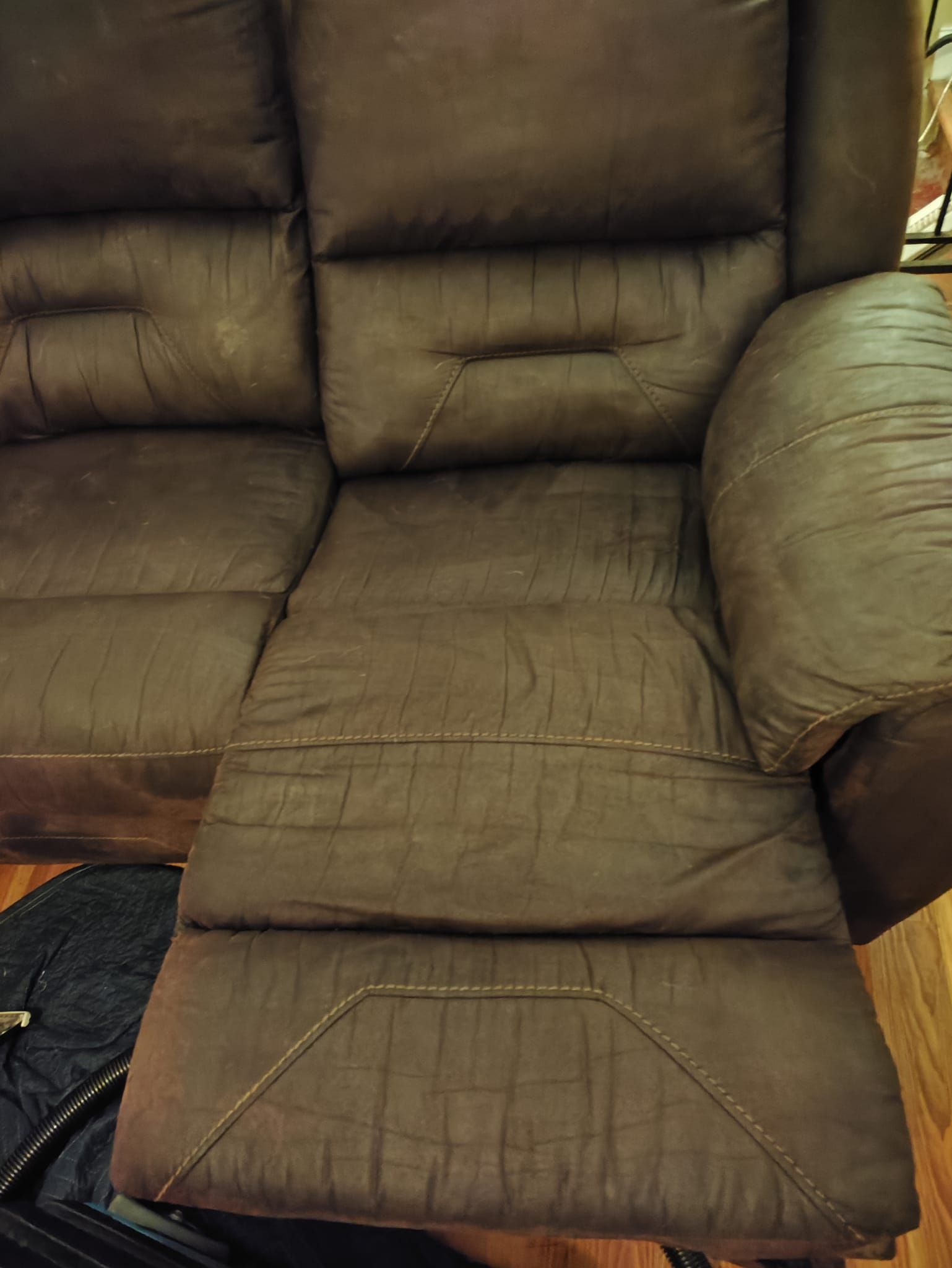 A brown leather recliner is sitting on a wooden floor.