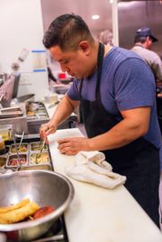 A man in an apron is preparing food in a kitchen.