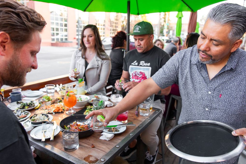 A man is serving food to a group of people at a table.