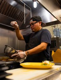 A man in an apron is preparing food in a kitchen.