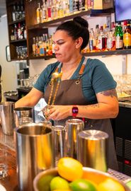 A woman is preparing a drink at a bar.