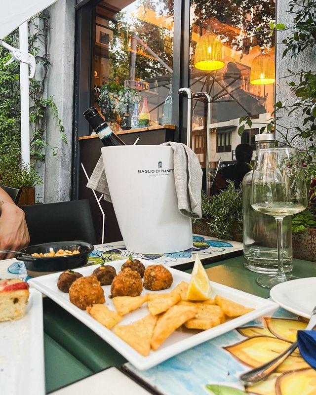 Una persona è seduta a un tavolo con un piatto di cibo e un secchio di vino.