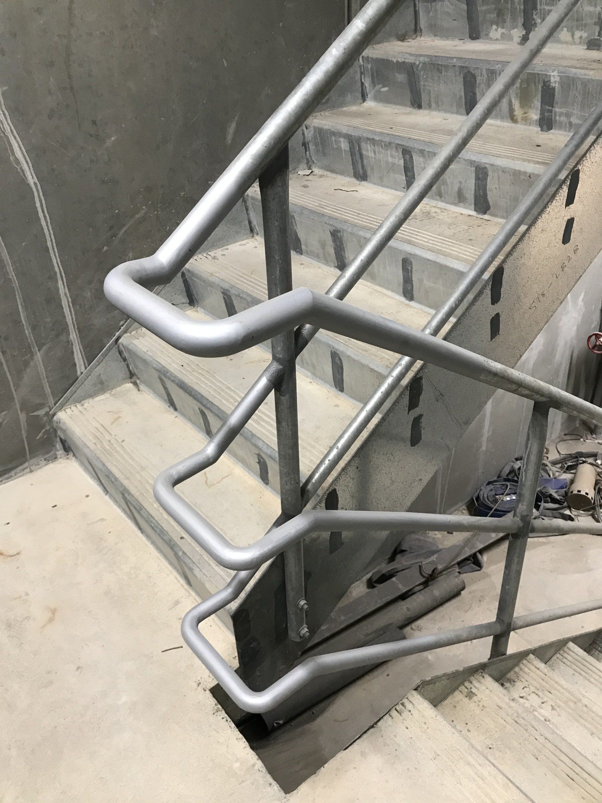 Galvanised steel fire stair handrails running down basement stairs