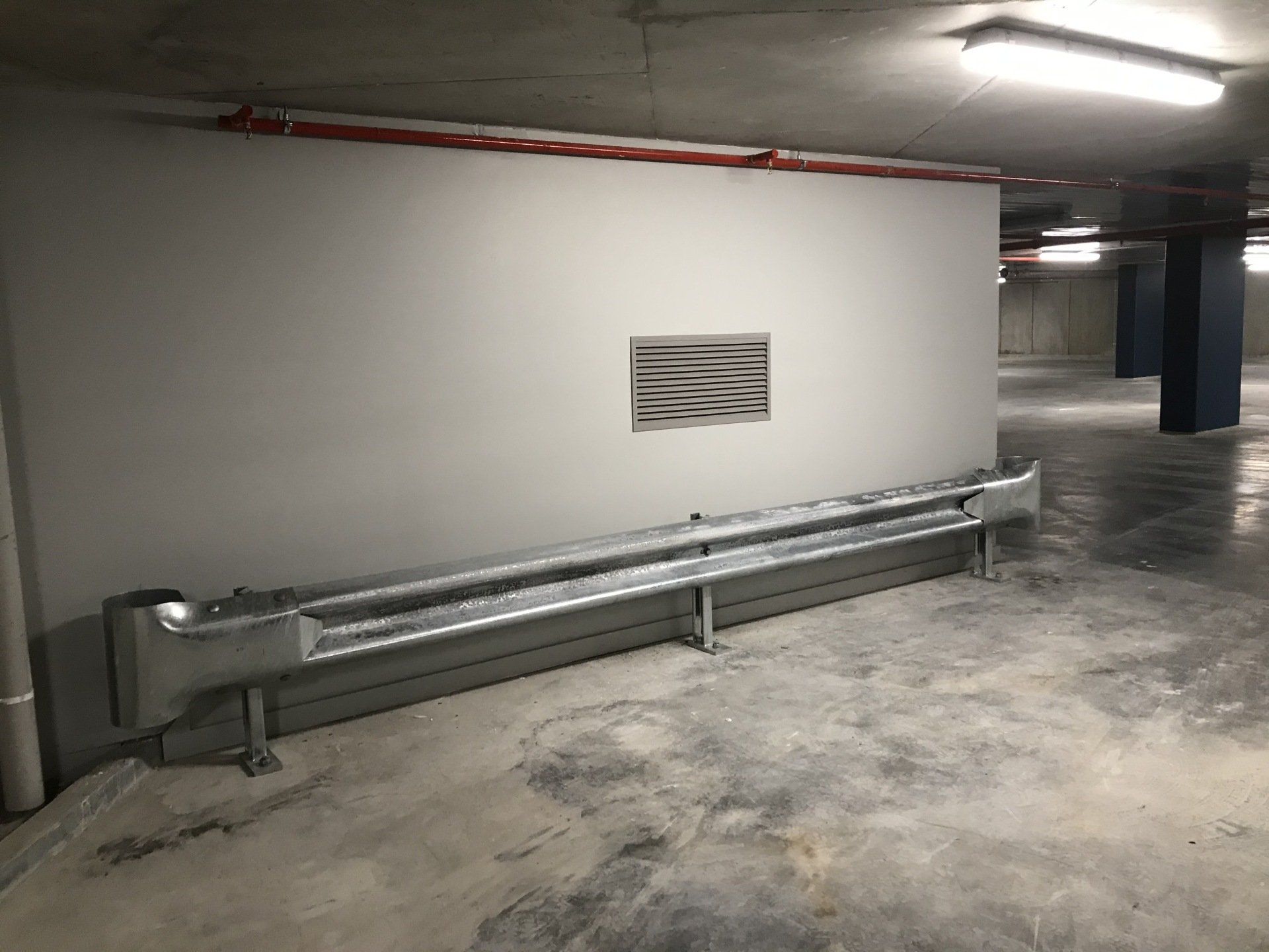Galvanised W beam style guard rail protecting a wall