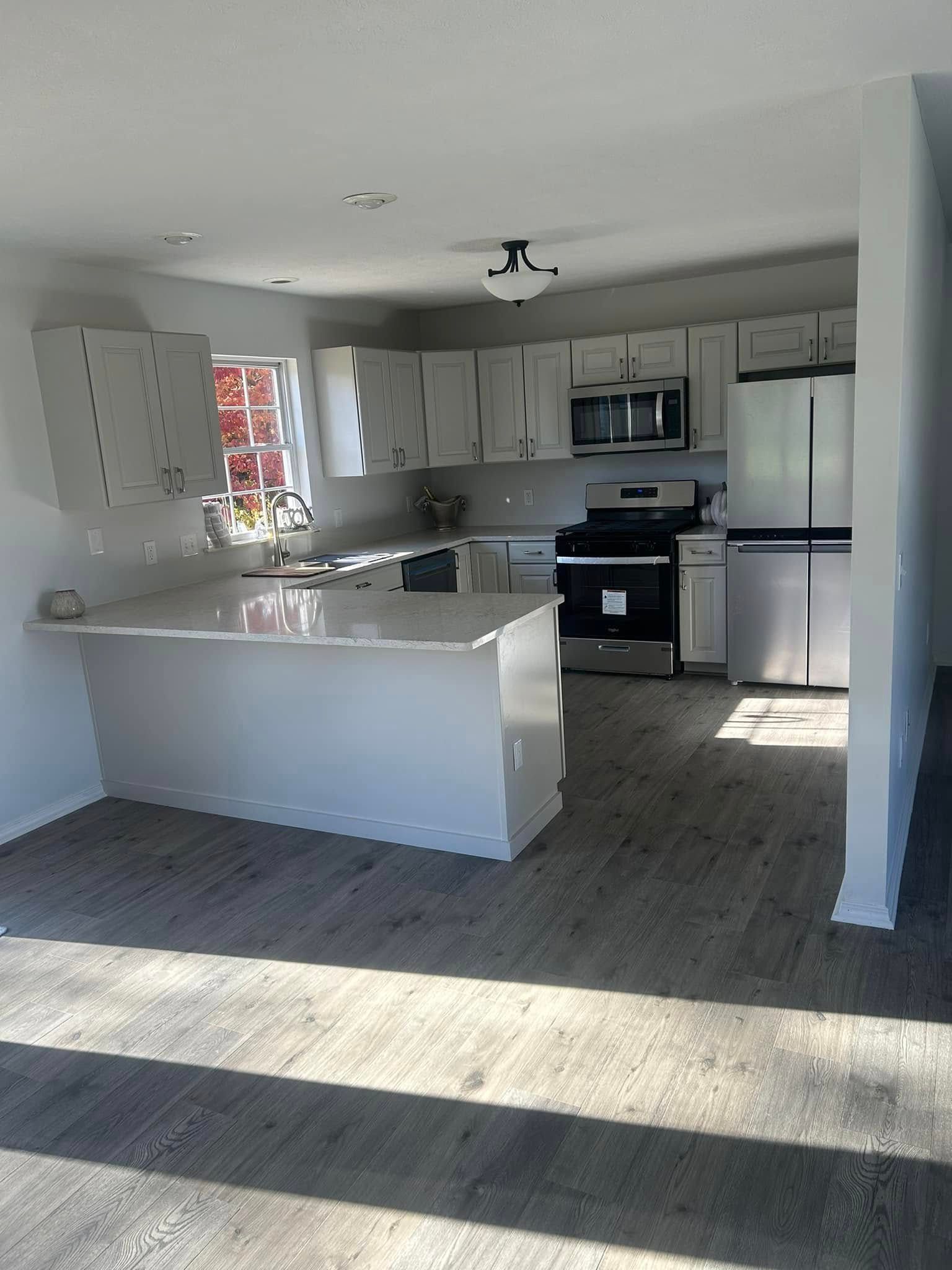 Modern kitchen with white cabinets, stainless steel appliances, and a breakfast bar.