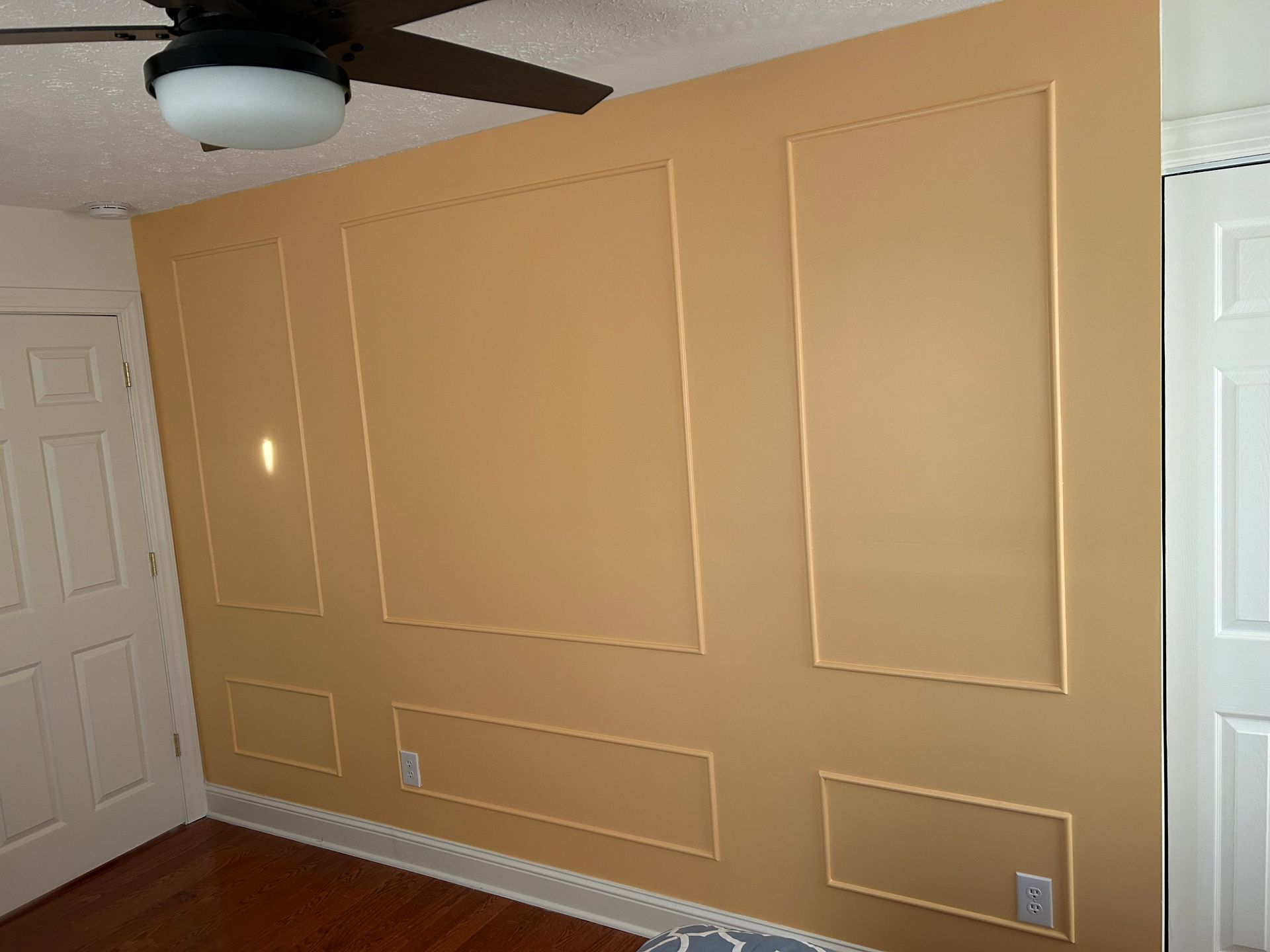 A peach-colored interior wall with decorative molding squares and rectangles above baseboards.