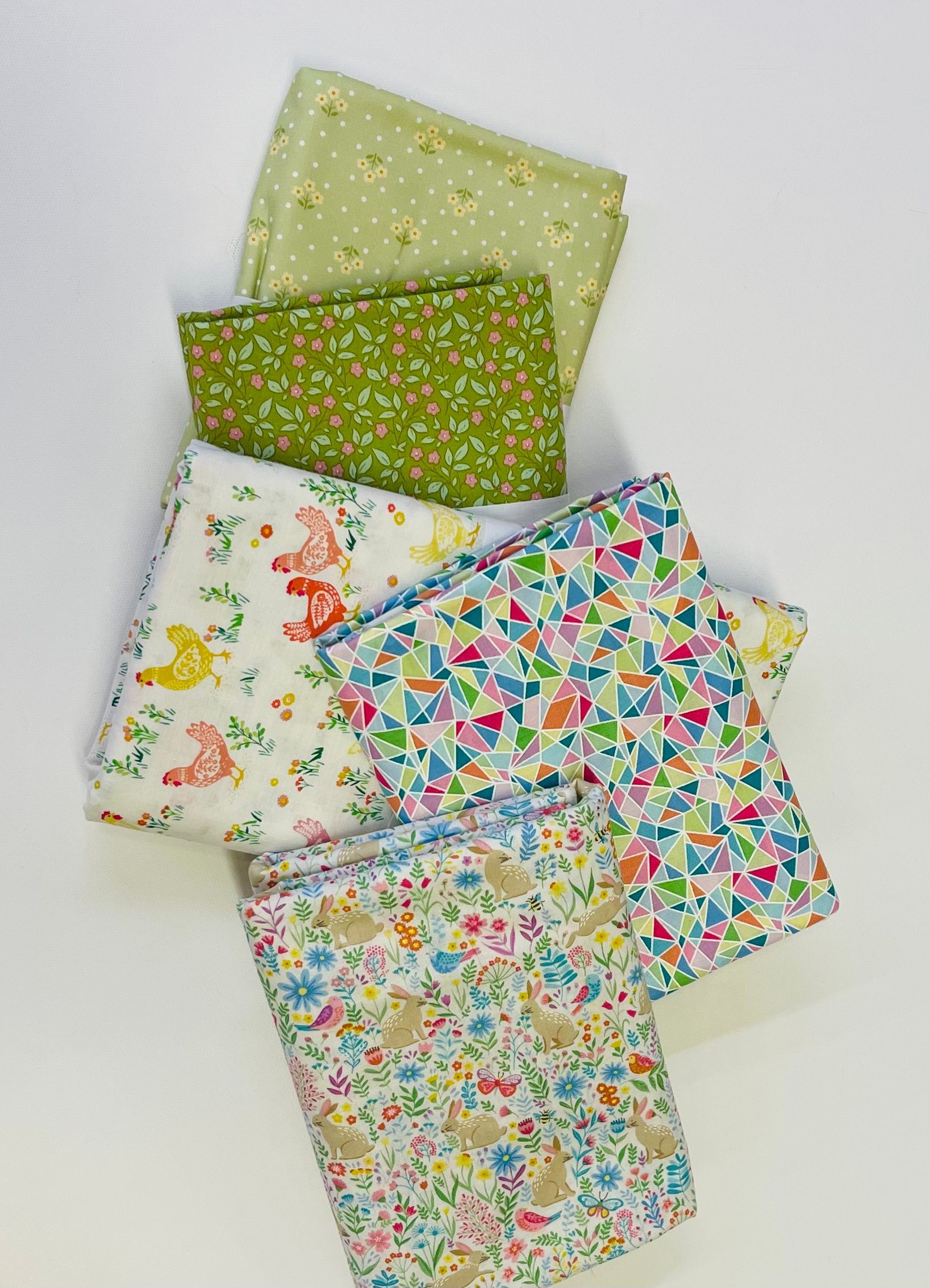 A bunch of spring themed fabrics are stacked on top of each other
