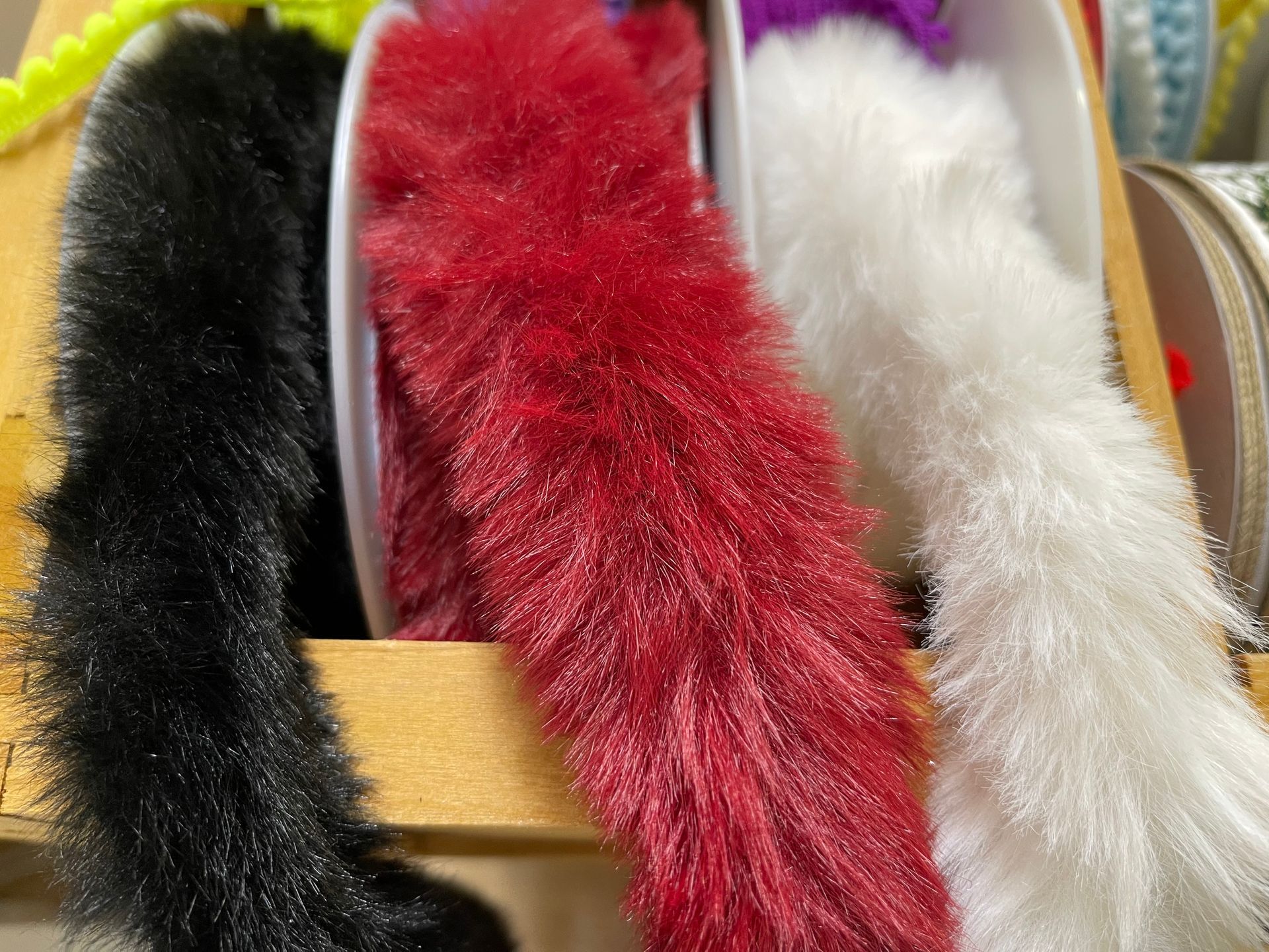 Close-up of spooled fluffy decorative trim in black, red, and white.