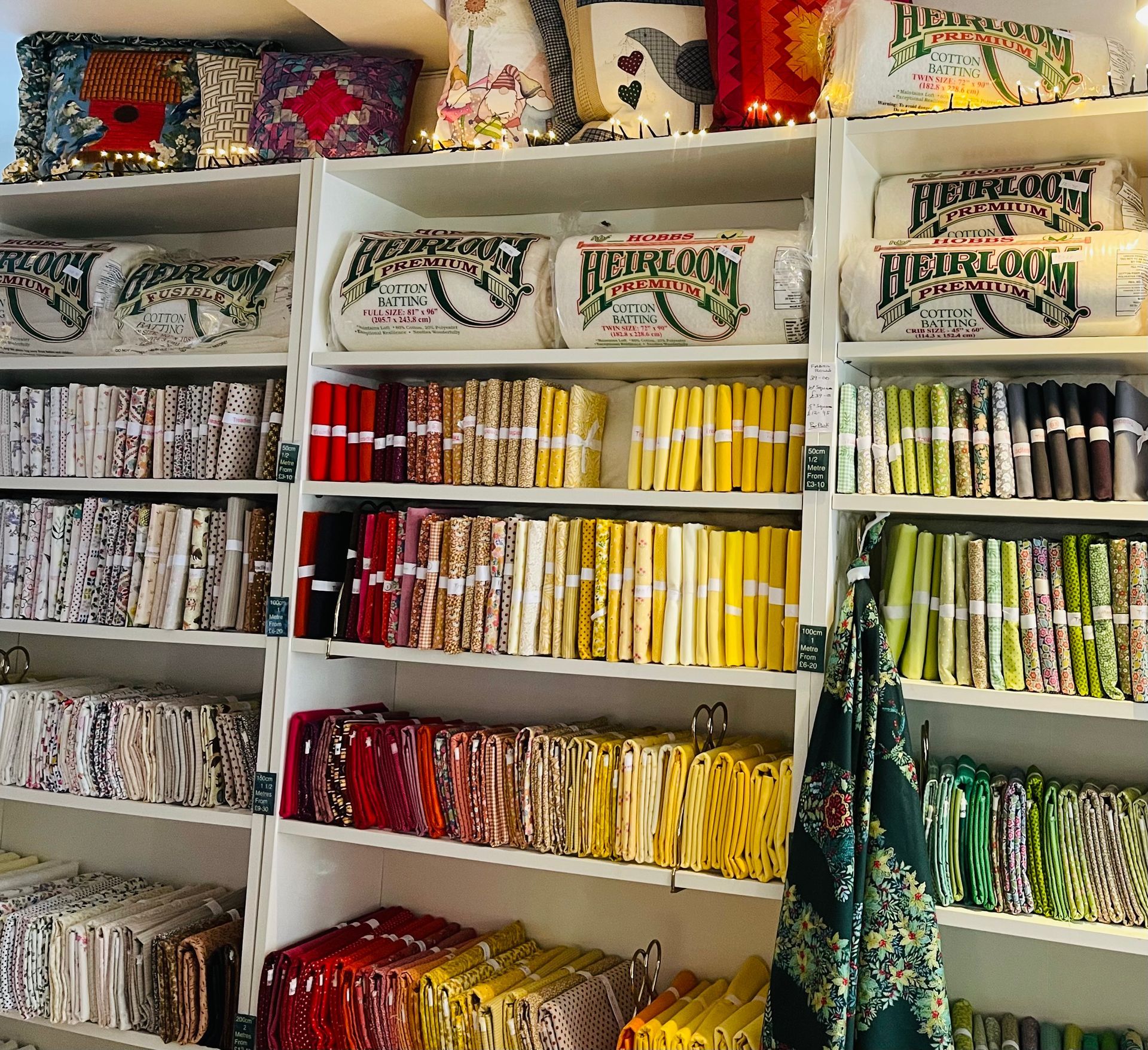 Shelves of neatly stacked folded fabrics and textiles in many colors in a fabric shop