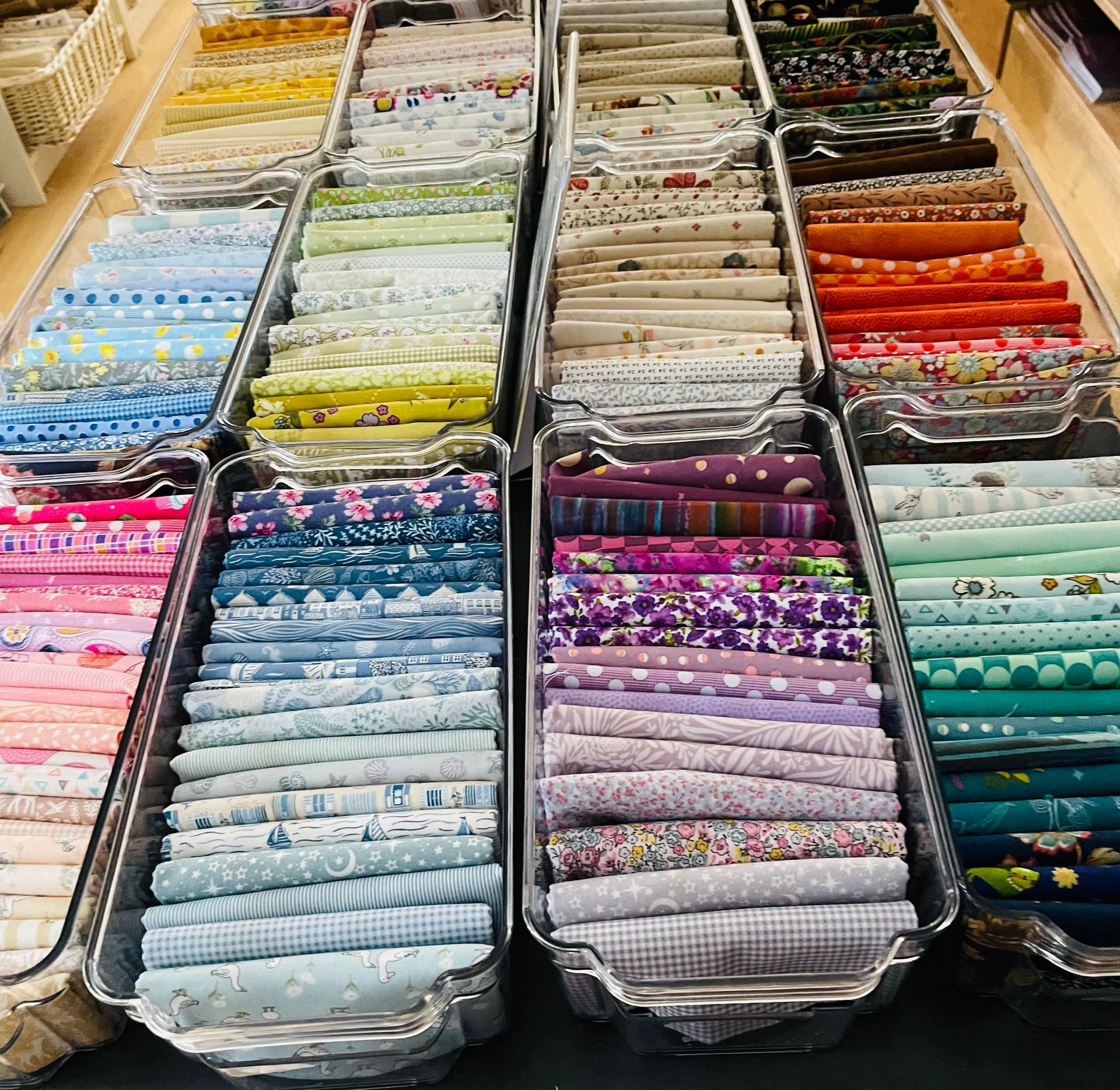 Organized rolls of colorful patterned fabric stacked in market display bins