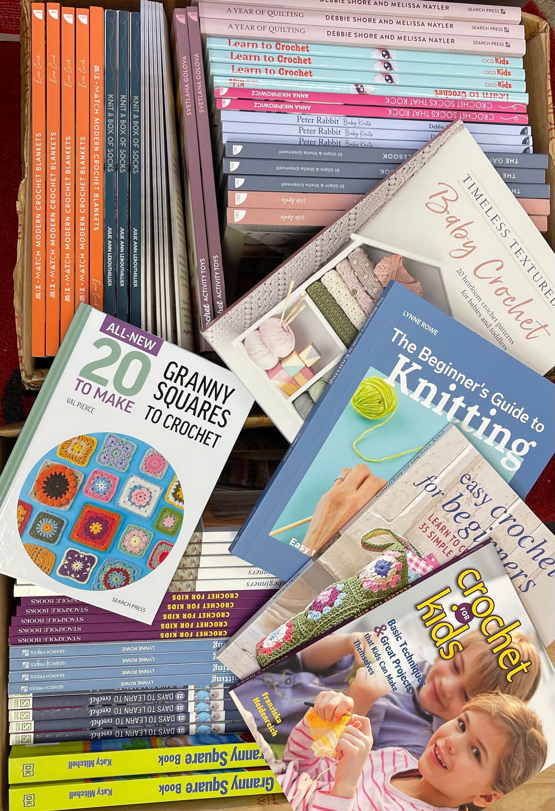 Stack of colorful craft and knitting books, including a