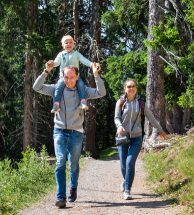 A man is carrying a child on his shoulders while walking down a path.