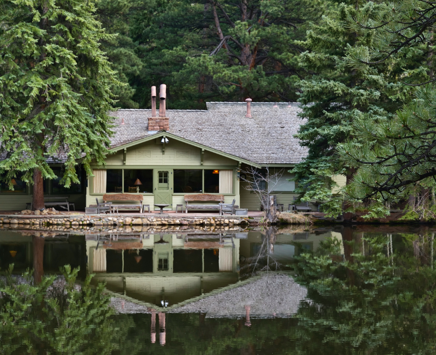 A house sits on the shore of a lake surrounded by trees