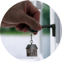 A person is holding a key with a house keychain attached to it.