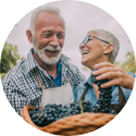 A man and a woman are laughing while holding a basket of grapes.