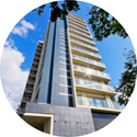A tall building with a blue sky in the background is in a circle.