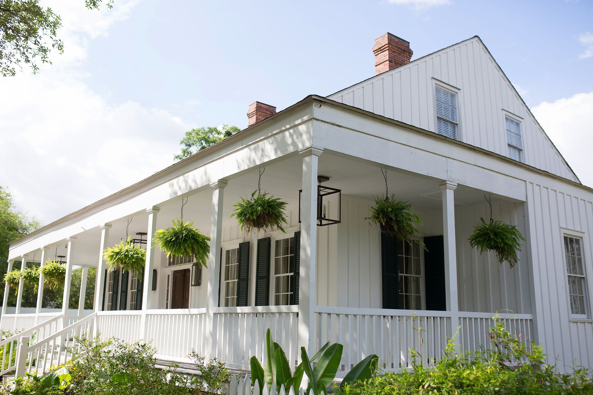 White house with porch and hanging plants.
