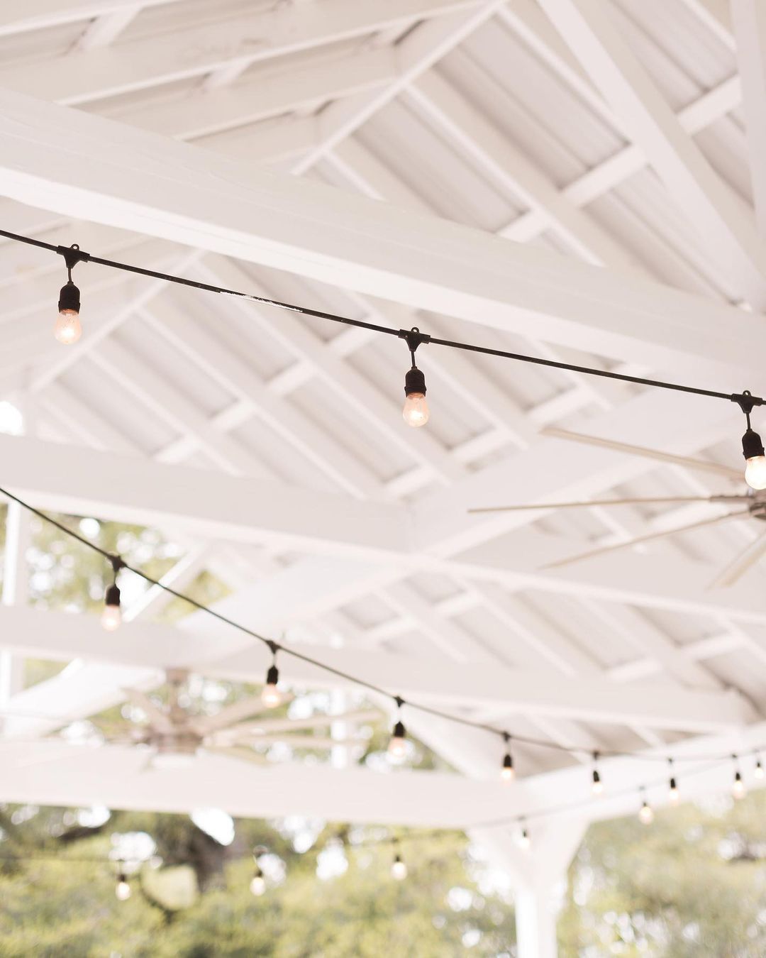 White pergola with string lights, outdoor setting.
