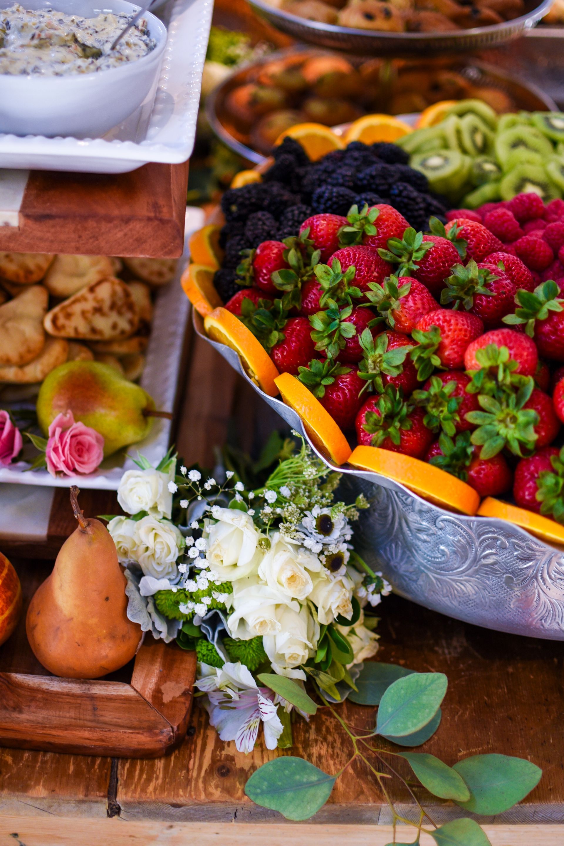 Fruit and pastry buffet with strawberries, blackberries, and kiwi, on a wooden table.