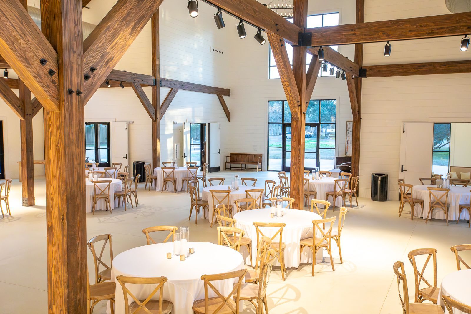 Event space with round tables, wood chairs, and exposed wooden beams.