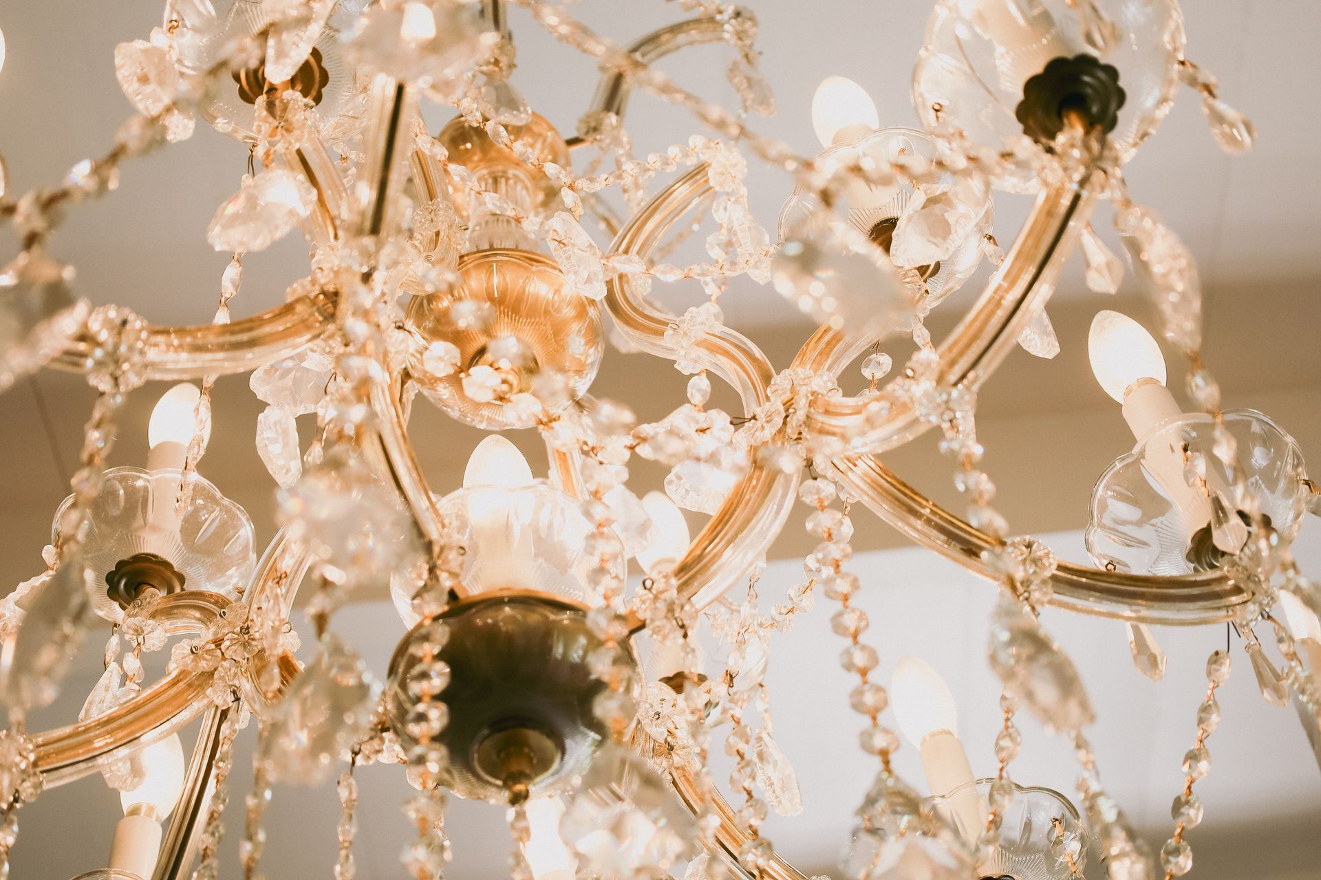 Close-up of a decorative crystal chandelier with many crystals and lights, against a light background.