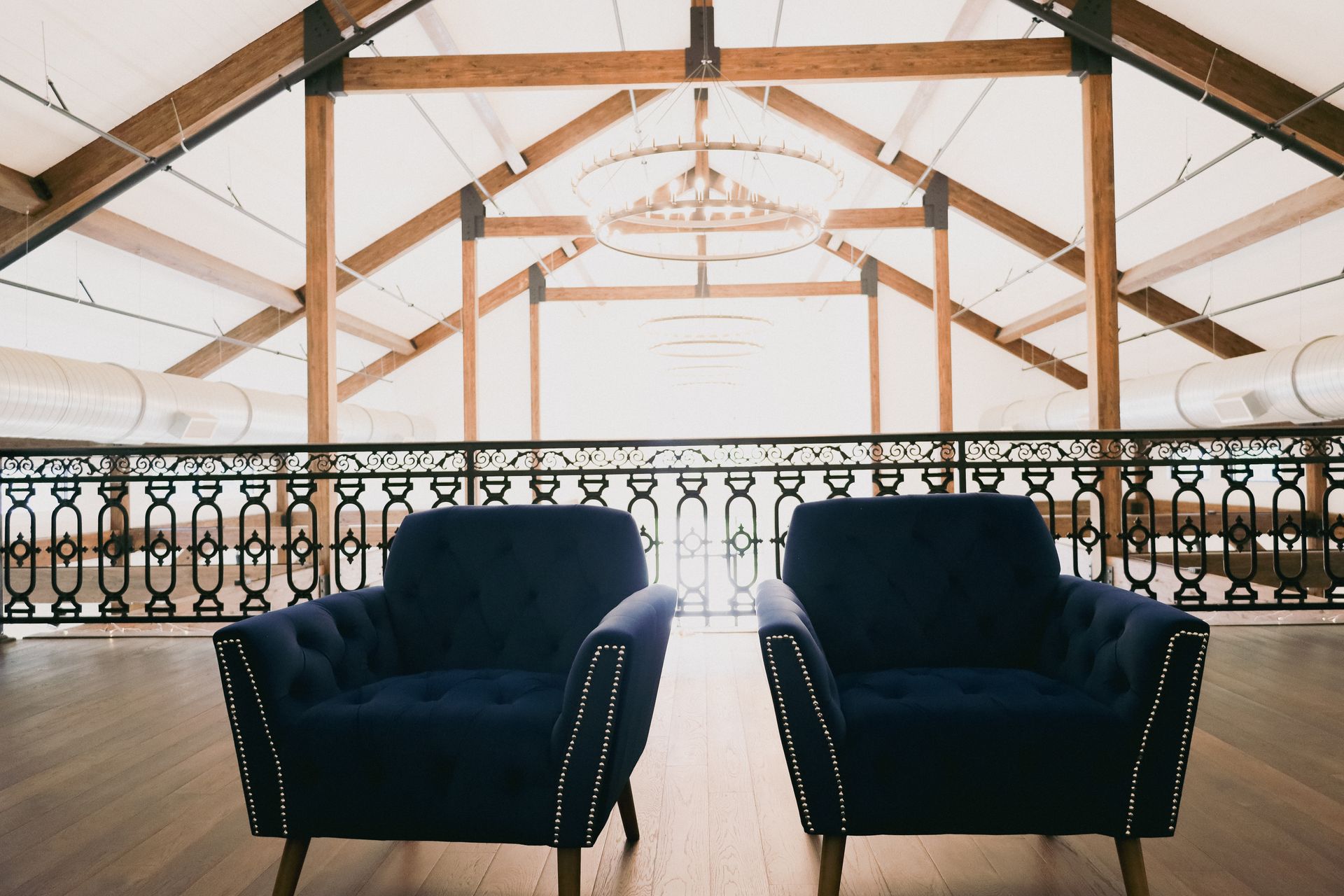 Two blue armchairs in front of a balcony with wooden beams, interior setting.