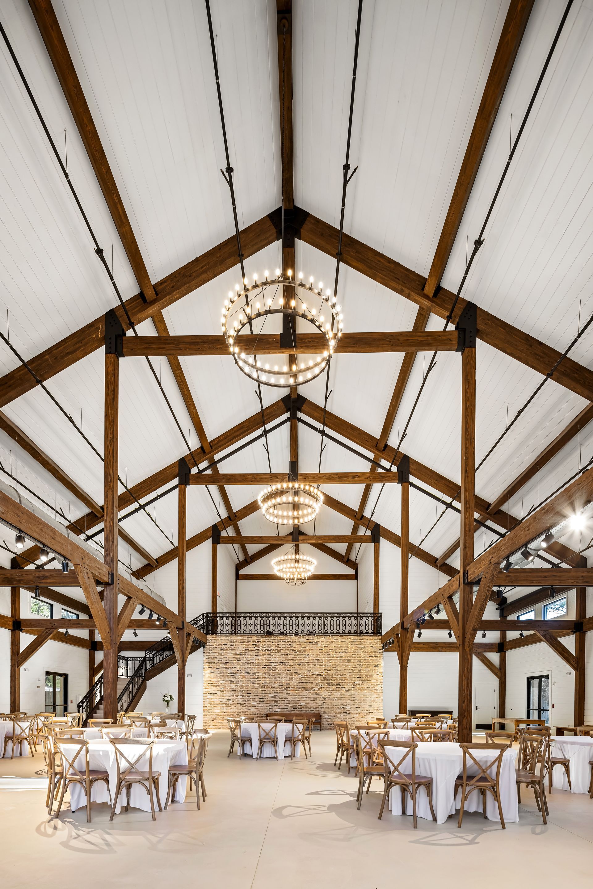 Event space interior with wooden beams, chandeliers, tables and chairs.