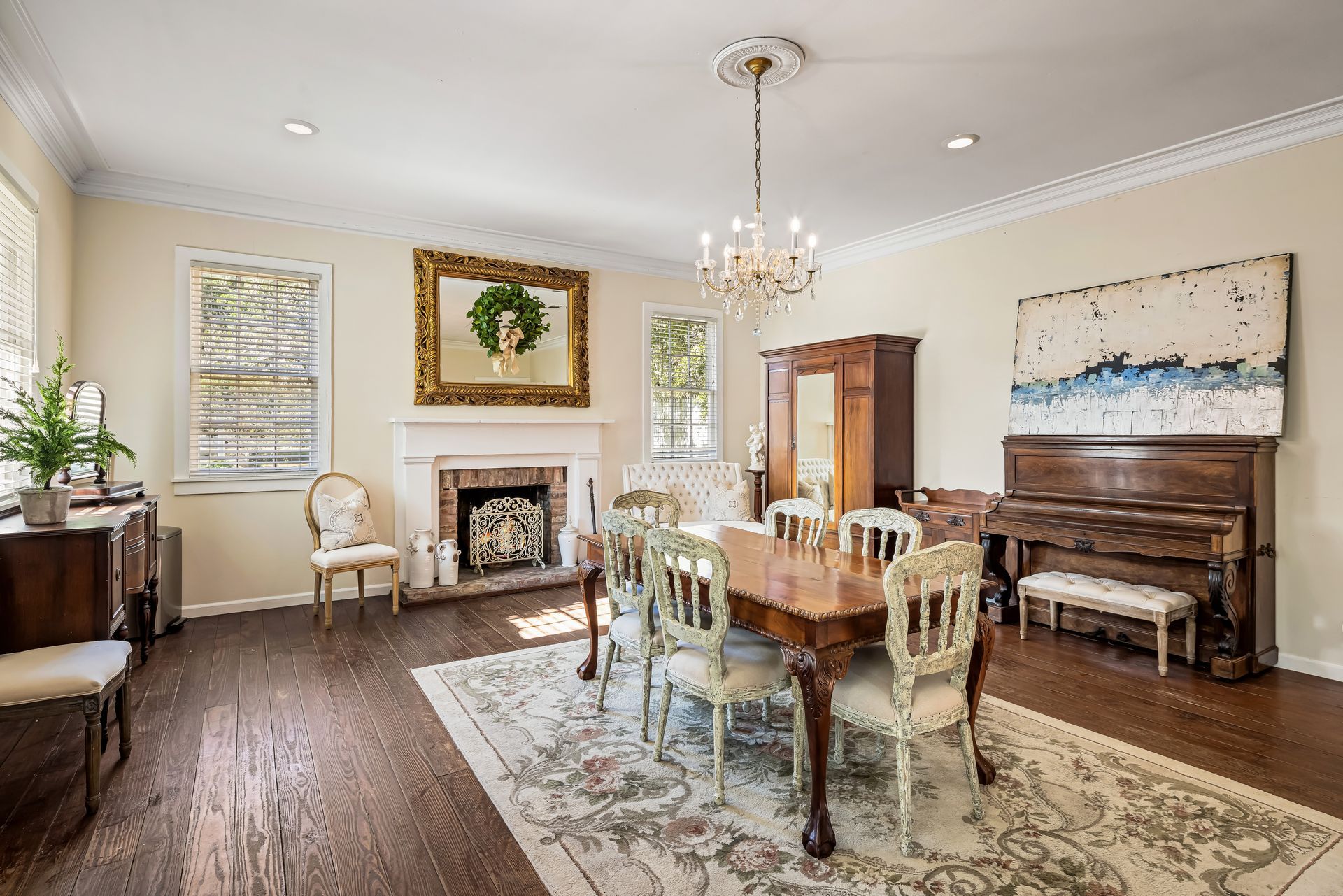 Elegant dining room with chandelier, table, chairs, fireplace, piano, and artwork.