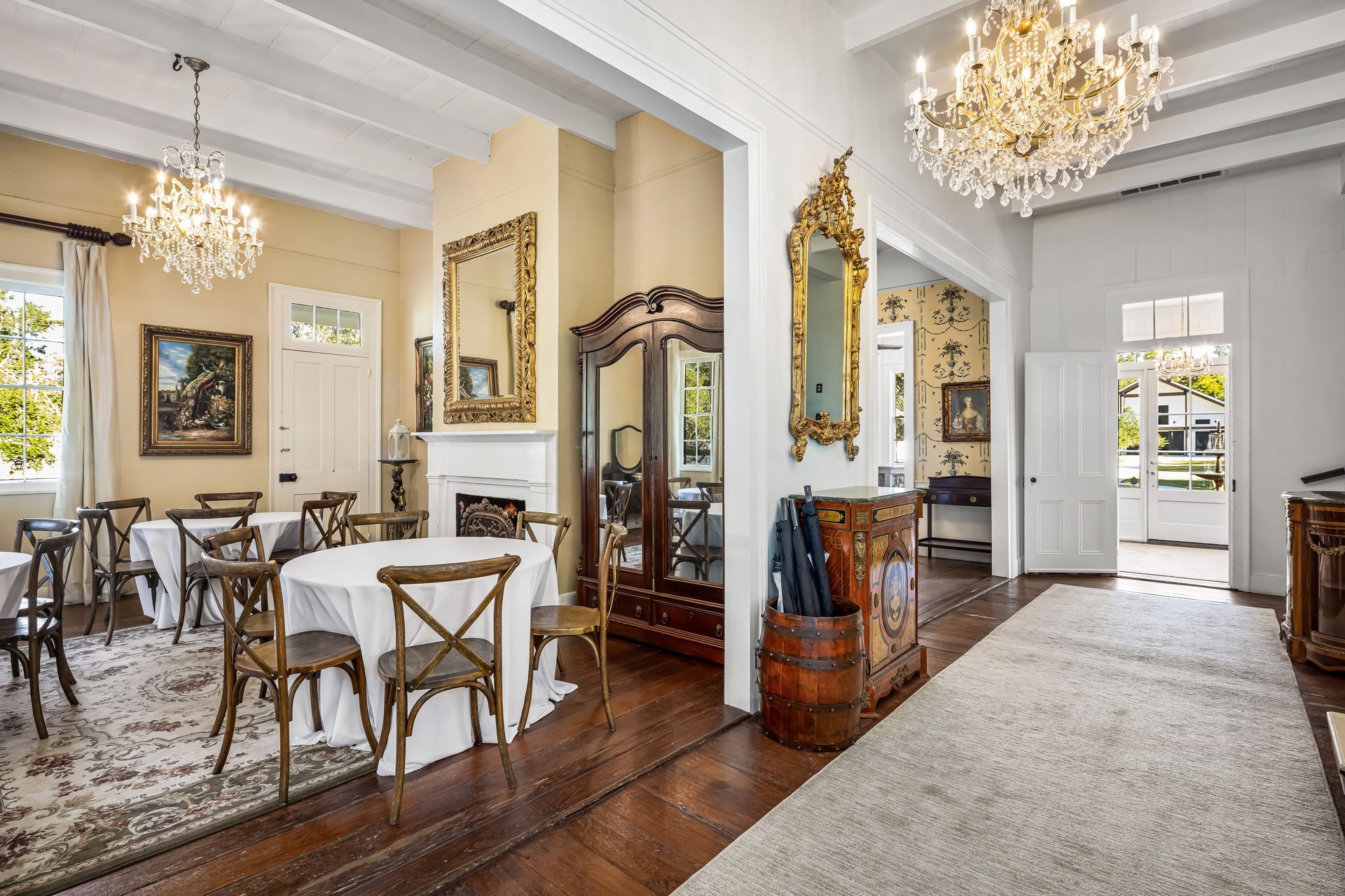 Elegant dining room with chandeliers, tables, and antique furniture.