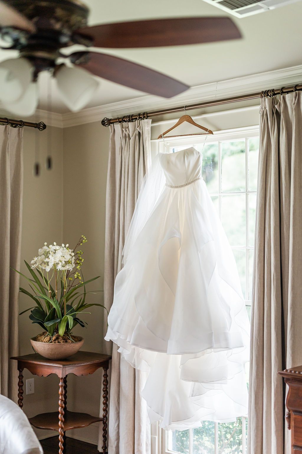 Wedding dress hanging in a window, with a long train and veil.