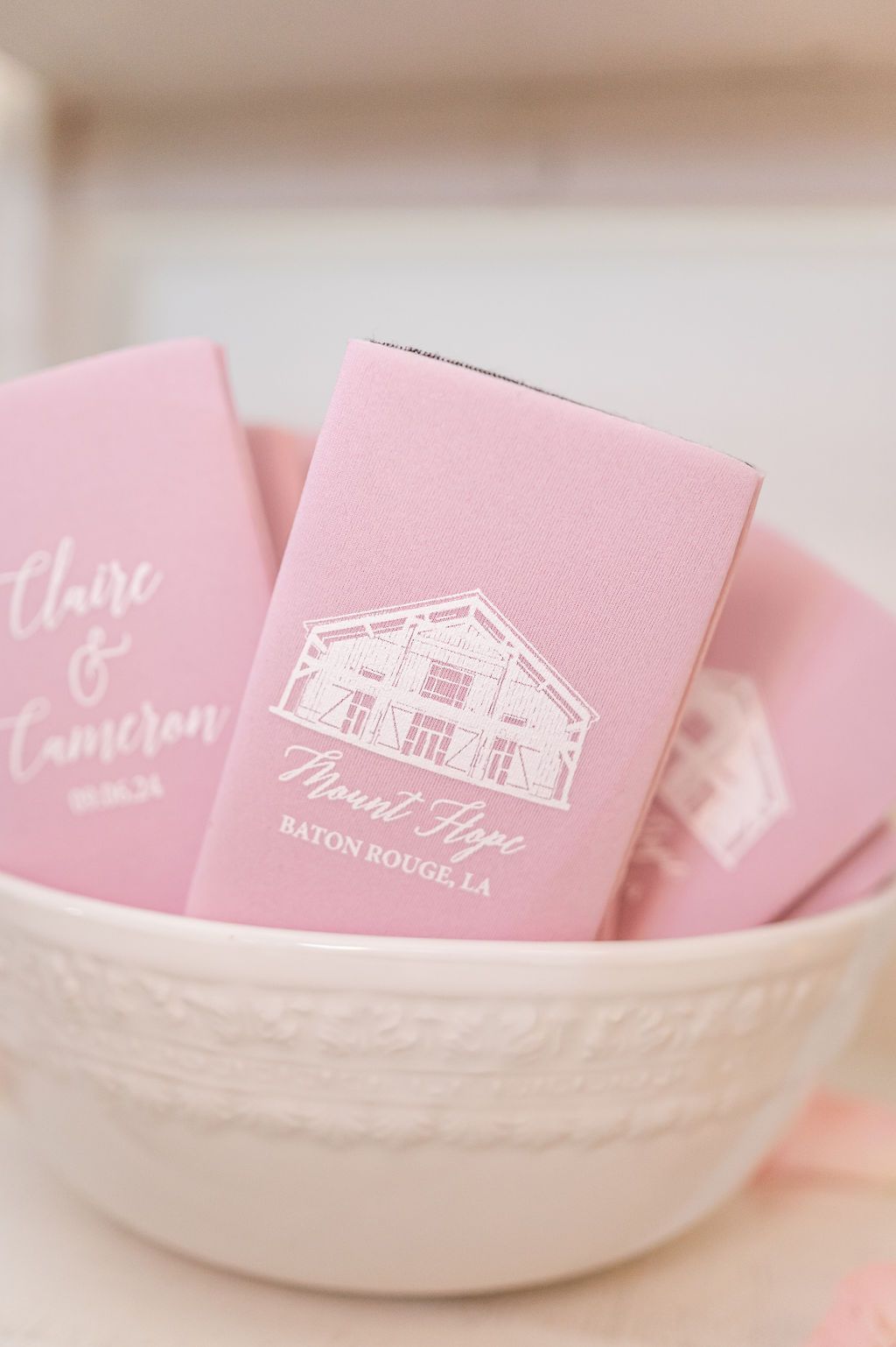 Pink wedding favors with white text and a barn graphic in a white bowl.
