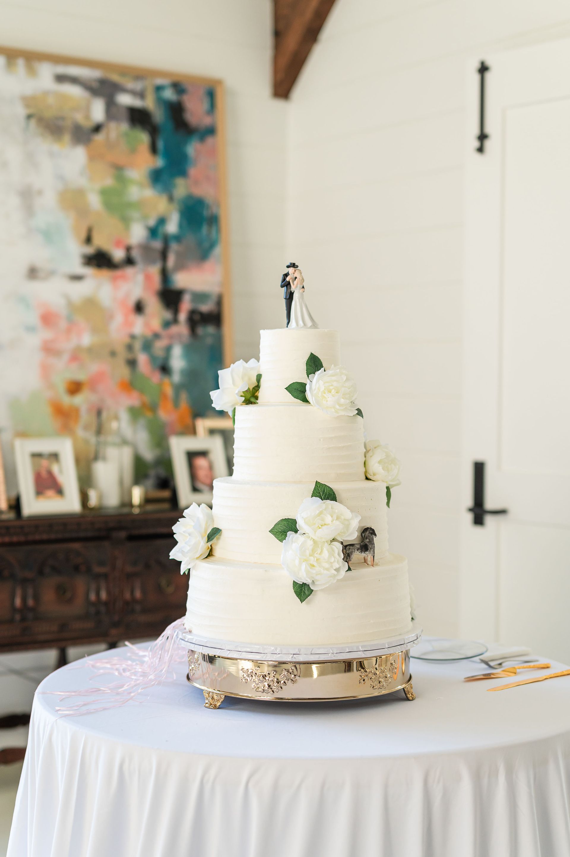 Wedding cake with white frosting, floral accents, and a couple figurine on a table.