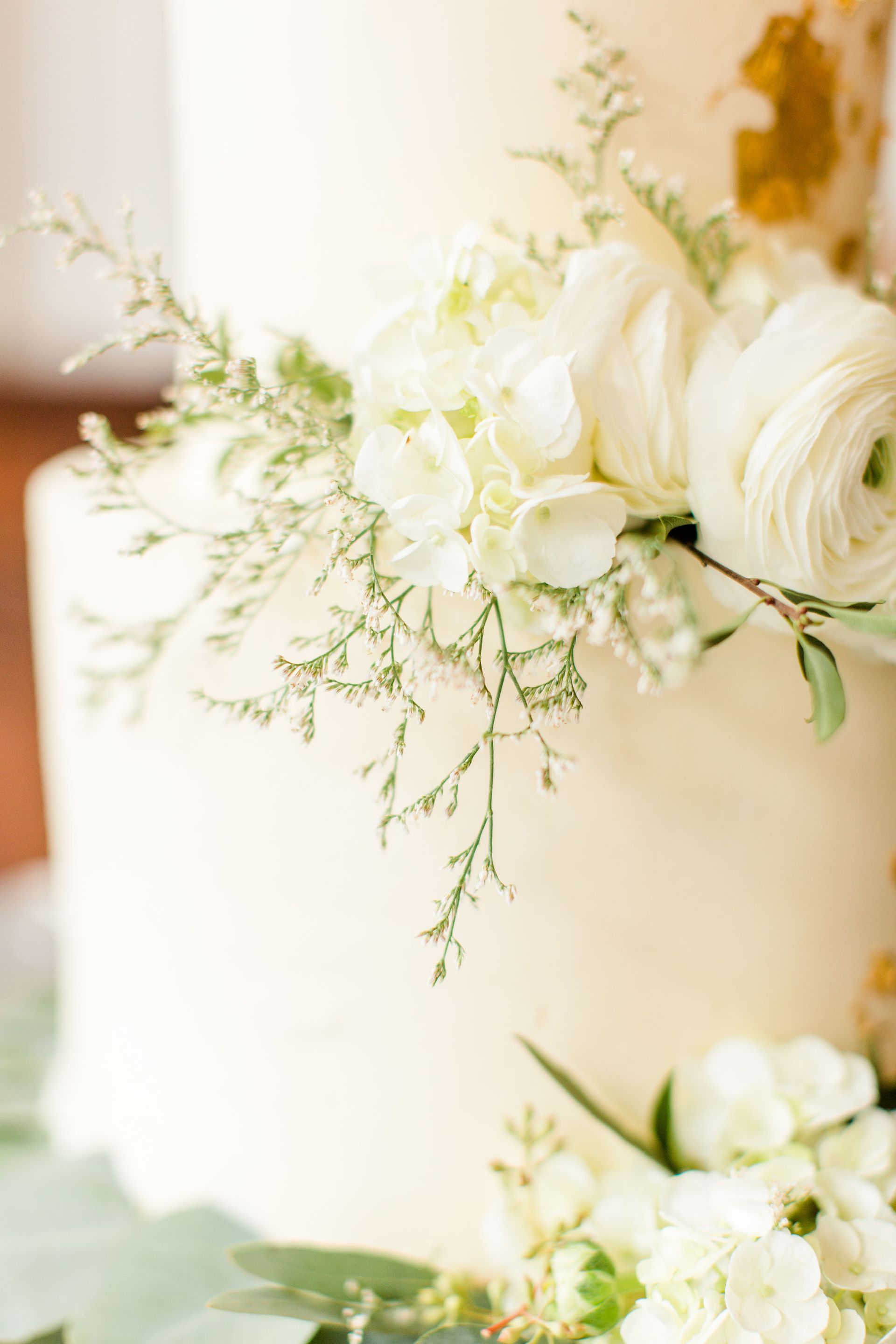 White wedding cake decorated with white flowers and greenery.