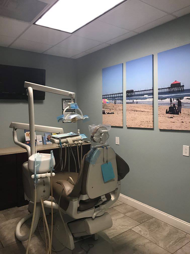 Dental office operatory with patient chair, dental equipment, and beach artwork on gray walls