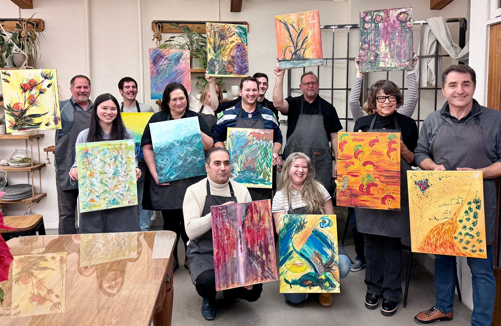 team of people holding colorful paintings