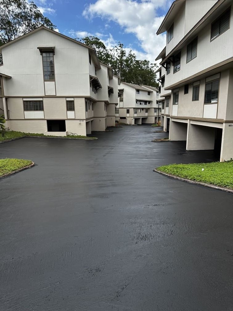 Apartment complex with a newly paved asphalt driveway under a cloudy sky.