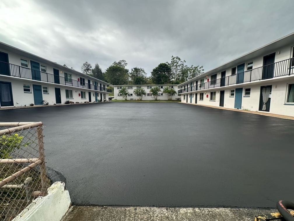 Asphalt parking area surrounded by two-story motel buildings, overcast sky overhead.