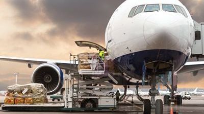 A large passenger jet is being loaded with cargo at an airport.