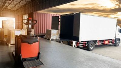 A white truck is parked in a warehouse next to a forklift.