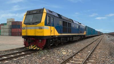 A blue and yellow train is on the tracks.