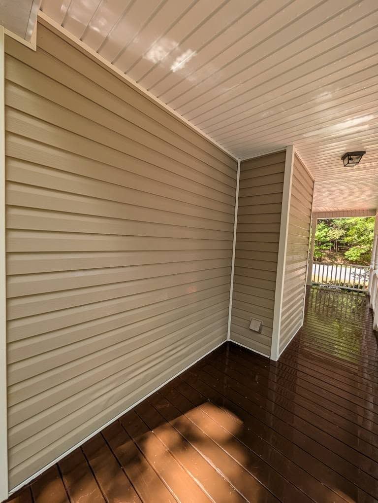 Tan siding and white trim on a porch, brown wooden floor, and white ceiling.
