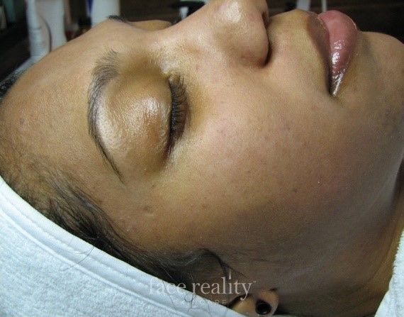Woman's face, eyes closed, in profile. Brown skin, pink lips, resting on a white towel.