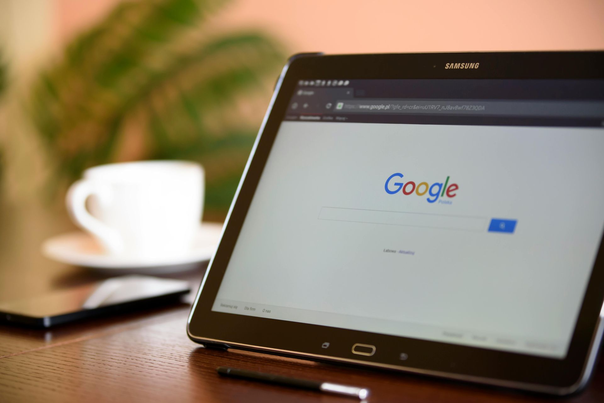 Tablet met de Google-zoekpagina open, naast een koffiekopje en een stylus.
