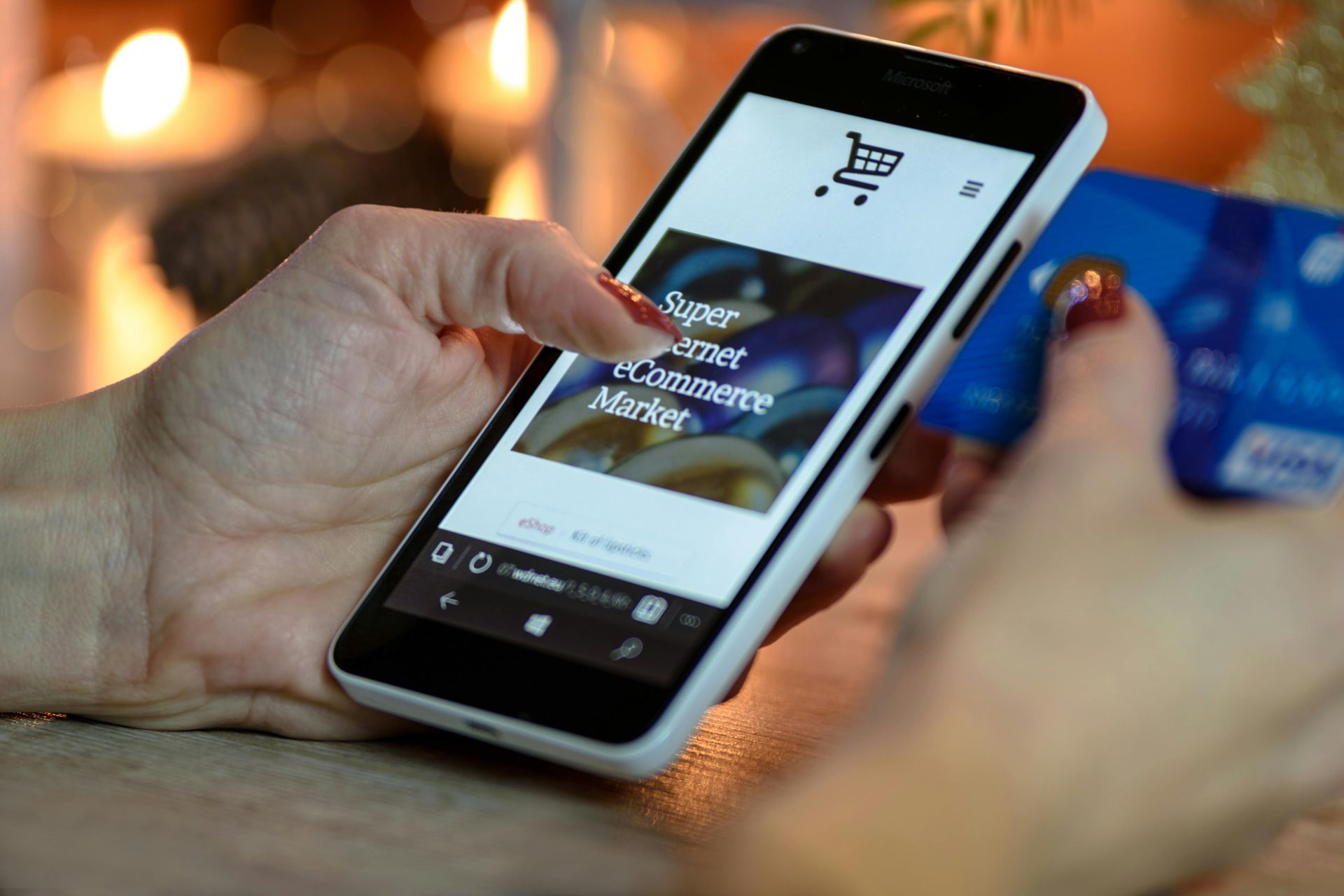 Een persoon met een smartphone waarop een webwinkel staat, en een creditcard in zijn hand.