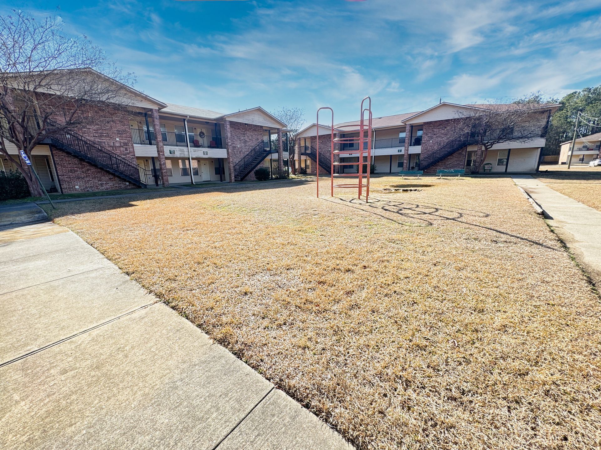 A playground in front of a brick apartment building.