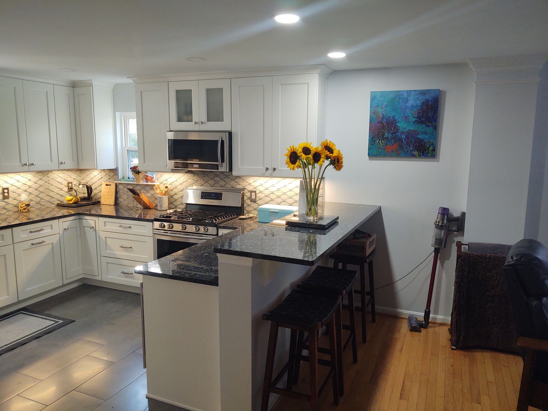A kitchen with a vase of sunflowers on the counter
